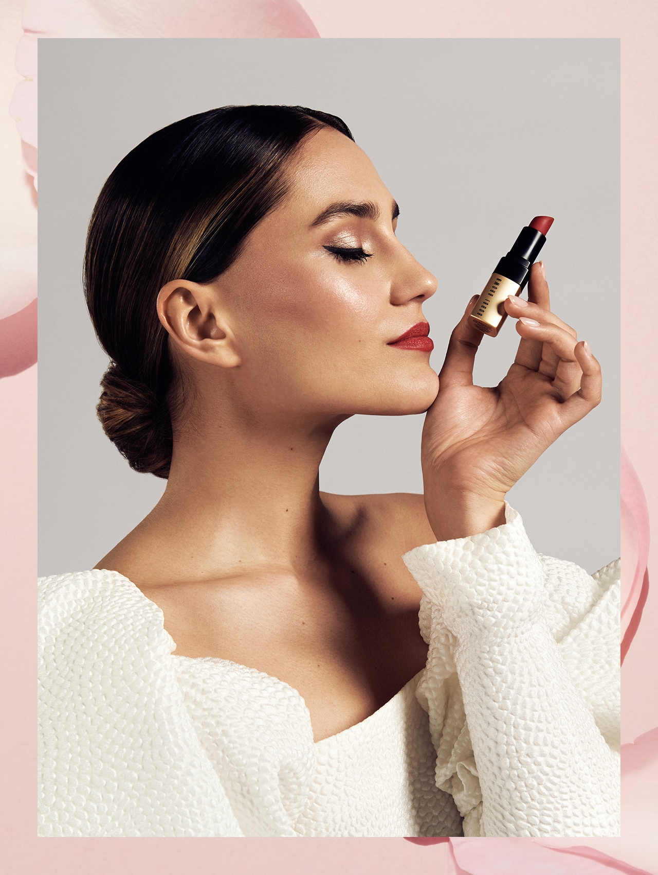 Imagine containing step 5 model applying lipstick, smiling while looking into compact Bobbi Brown mirror