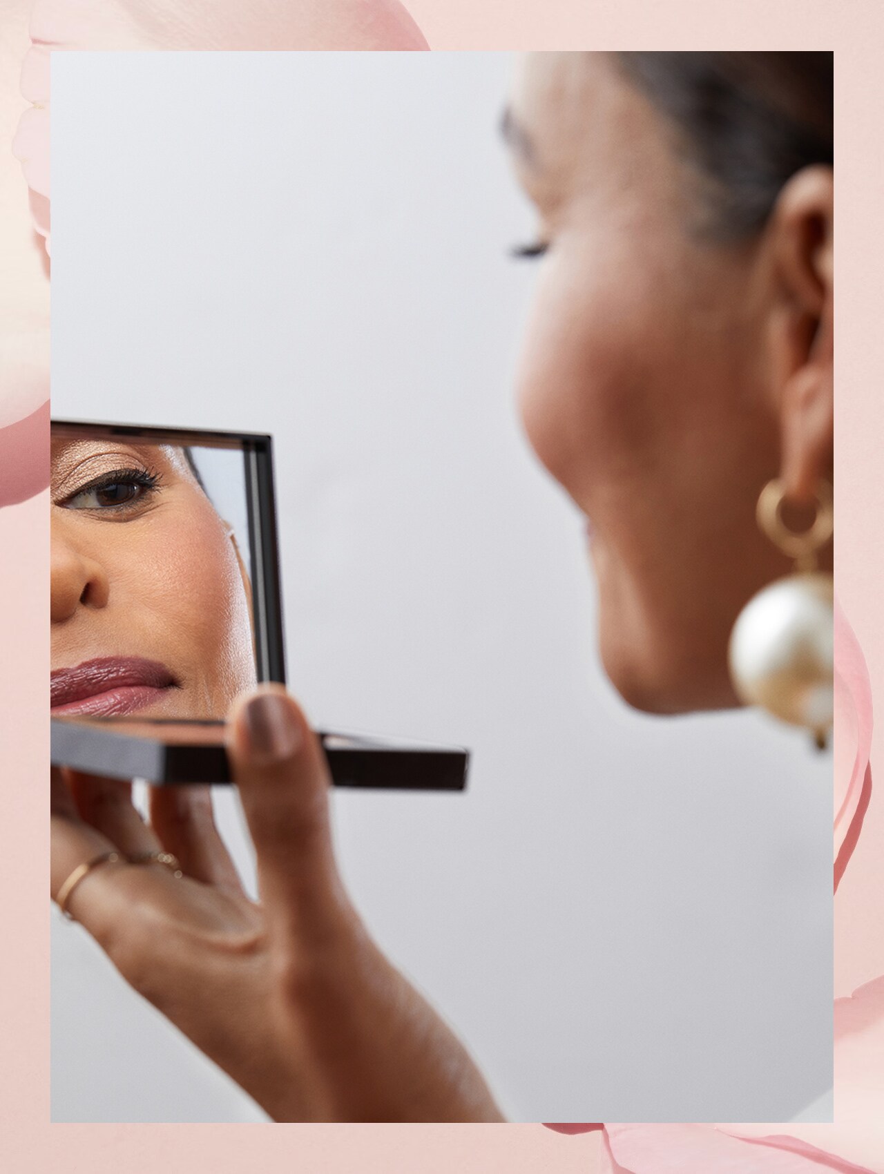 Imagine containing step 5 model applying lipstick, smiling while looking into compact Bobbi Brown mirror